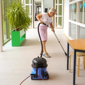 Schoonmaakster is bezig met stofzuigen