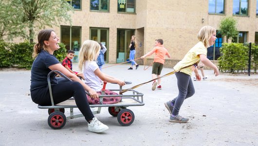 Juf en kinderen spelen buiten met skelter